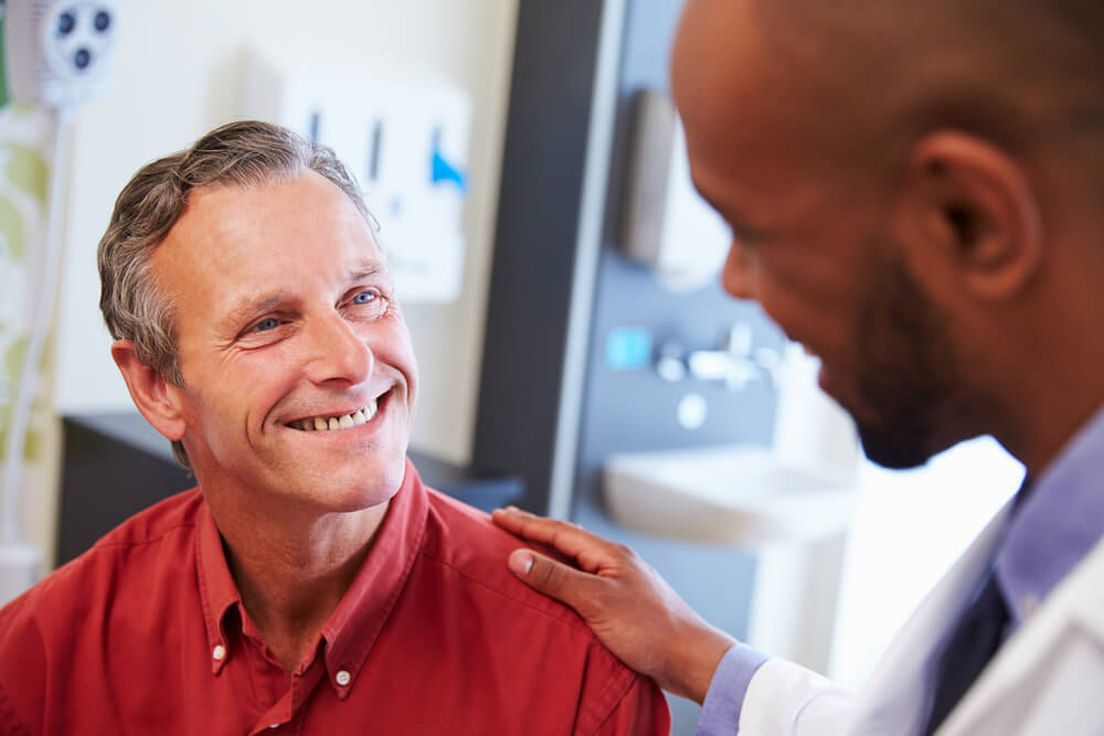 Smiling patient, doctor with his hand on patient's shoulder